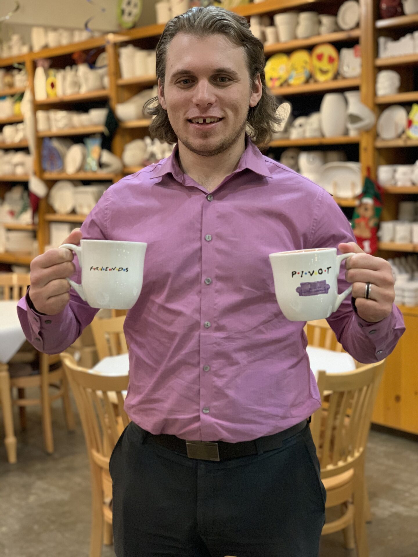 Person holding cups of coffee and smiling for the camera