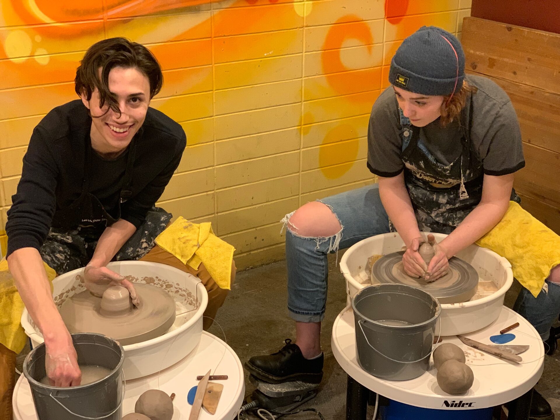 two young adults making pots