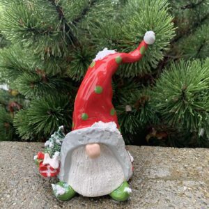 Cute gnome figurine with a tall red hat and white beard in a garden.